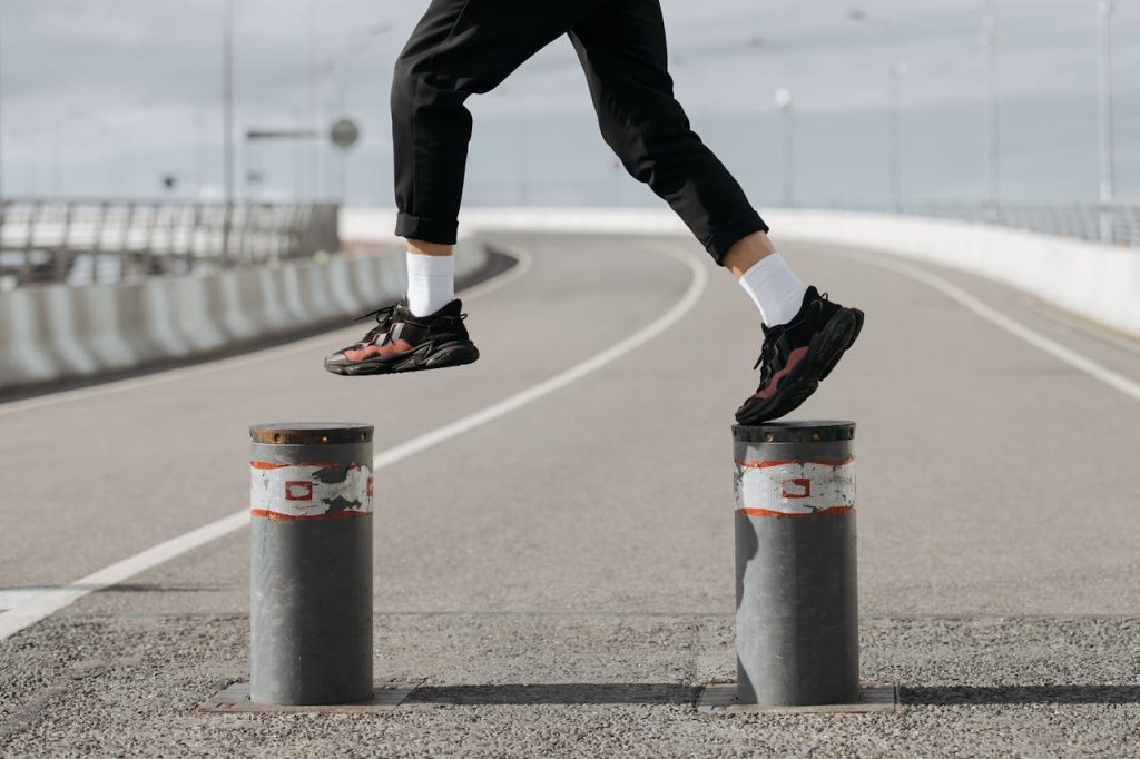 Athlete in motion leaping between street pillars, showcasing energy and agility.